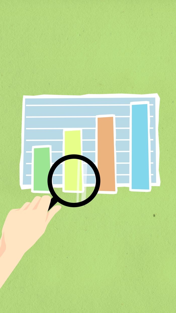 Top-down view of a decorative cardboard illustration of a hand holding a magnifying glass over a diagram with columns on a green background